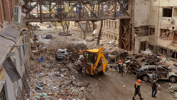 Los trabajadores comunales limpian los edificios destruidos tras el bombardeo, matando a dos personas e hiriendo a otras dieciocho, según la oficina del fiscal de la región de Járkov, en la ciudad ucraniana de Járkov el 16 de abril de 2022. - Rusia invadió Ucrania el 24 de febrero de 2022. (Foto de SERGEY BOBOK / AFP)