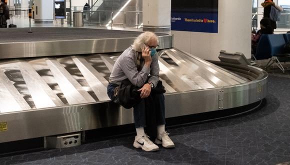 Un viajero se sienta en el reclamo de equipaje en el aeropuerto LaGuardia en Nueva York, el 24 de diciembre de 2021. (Foto: Yuki IWAMURA / AFP)