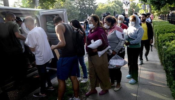 Migrantes de Venezuela, que abordaron un autobús en Texas, esperan ser transportados a una iglesia local por voluntarios después de ser dejados frente a la residencia de la vicepresidenta de EE. UU. Kamala Harris, en el Observatorio Naval en Washington, DC, el 15 de septiembre de 2022. (Foto de Stefani Reynolds / AFP)