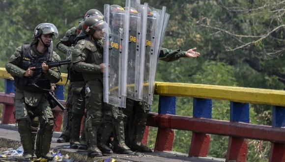 Miembros de la Guardia Nacional Bolivariana de Venezuela se protegen de los manifestantes que tiran piedras desde debajo del puente internacional en Urena, Venezuela. (Foto: AFP)