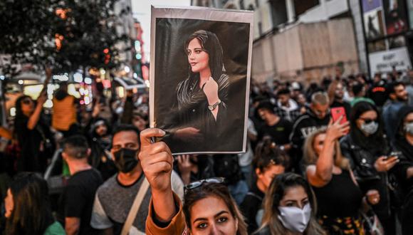 A protester holds a portrait of Mahsa Amini  during a demonstration in support of Amini, a young Iranian woman who died after being arrested in Tehran by the Islamic Republic's morality police, on Istiklal avenue in Istanbul on September 20, 2022. - Amini, 22, was on a visit with her family to the Iranian capital when she was detained on September 13 by the police unit responsible for enforcing Iran's strict dress code for women, including the wearing of the headscarf in public. She was declared dead on September 16 by state television after having spent three days in a coma. (Photo by OZAN KOSE / AFP)
