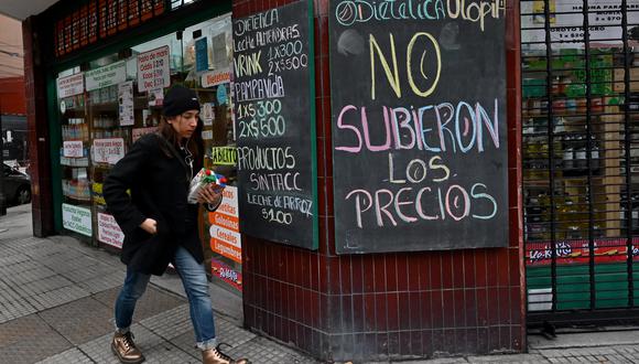 Una mujer pasa frente a un cartel que dice "Los precios no subieron" afuera de una tienda en Buenos Aires, Argentina, el 6 de julio de 2022. (Foto: Luis ROBAYO / AFP)