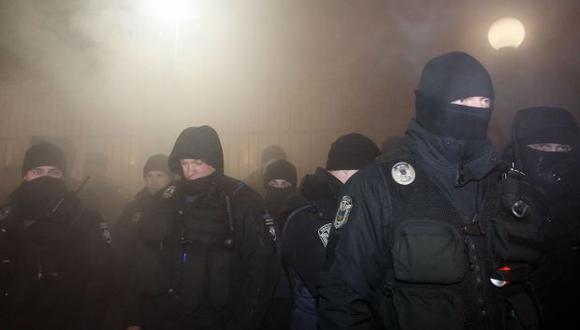 Los policías ucranianos protegen el edificio de la embajada rusa con humo detrás durante el mitin de activistas ucranianos en Kiev, Ucrania. (Foto: EFE)
