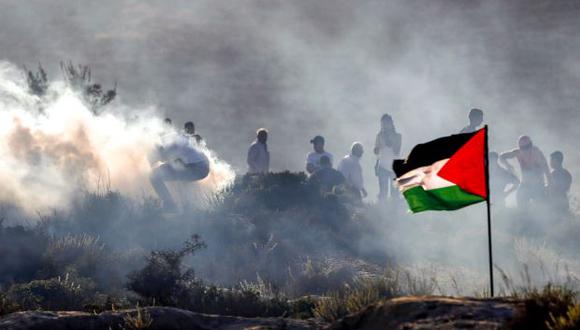 Manifestantes palestinos huyen de las latas de gases lacrimógenos que se reciben durante los enfrentamientos con las fuerzas de seguridad israelíes en la aldea de Ras Karkar. (Foto referencial: AFP)