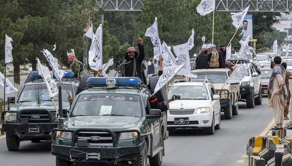 Los combatientes talibanes sostienen armas mientras viajan en un convoy para celebrar el día de su victoria en el área de Bibi Mahro en Kabul el 15 de agosto de 2022. (Foto de Wakil KOHSAR / AFP)