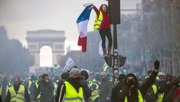 Una mujer grita consignas subida a un semáforo durante una protesta en los Campos Elíseos en París (Francia). (Foto: EFE)