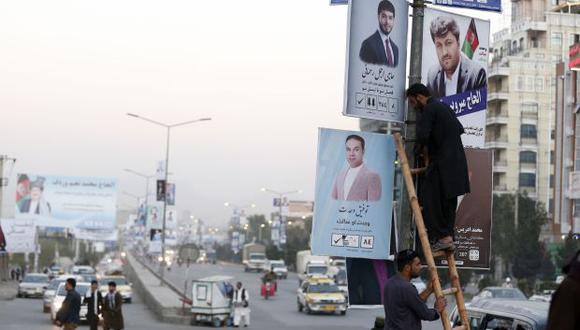 Hombres afganos instalan un póster de la campaña de un candidato para las próximas elecciones parlamentarias en el centro de Kabul, Afganistán. (Foto: EFE)