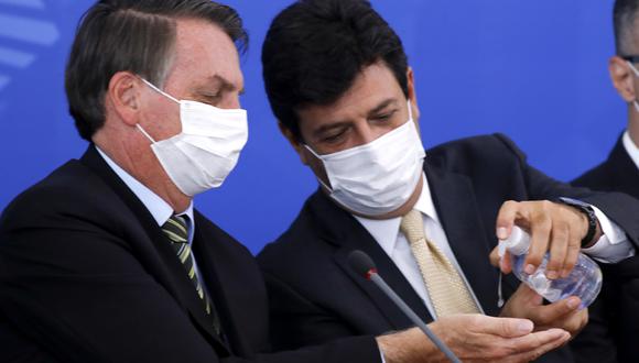 El presidente brasileño, Jair Bolsonaro, y su ministro de Salud, Luiz Henrique Mandetta, desinfectan sus manos con máscaras faciales durante una conferencia de prensa relacionada con el nuevo coronavirus. La relación entre ambos se quebró. (Foto: AFP/Sergio Lima)