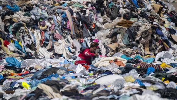 En esta foto de archivo tomada el 26 de septiembre de 2021, una mujer busca ropa usada entre toneladas desechadas en el desierto de Atacama, en Alto Hospicio, Iquique, Chile. (Foto: Martin BERNETTI / AFP)