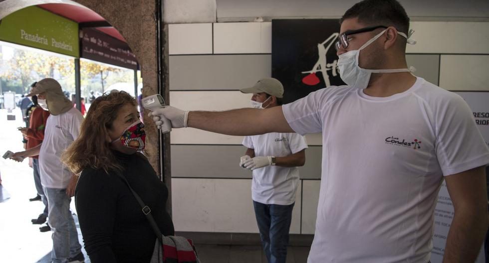 Imagen referencial. Un trabajador de seguridad verifica la temperatura a una persona como medida preventiva después del brote del coronavirus en Santiago de Chile. (Martín BERNETTI / AFP).