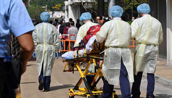 Médicos de ambulancia con ropa protectora para protegerse contra el covid-19 ingresan a la urbanización de Kwai Chung, donde se descubrió un grupo reciente de casos de coronavirus en Hong Kong el 27 de enero de 2022. (Foto: Peter PARKS / AFP)