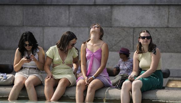 Un grupo de mujeres se refresca sumergiendo sus pies en la fuente de Trafalgar Square, en el centro de Londres, el 18 de julio de 2022. (Foto: Niklas HALLE'N / AFP)