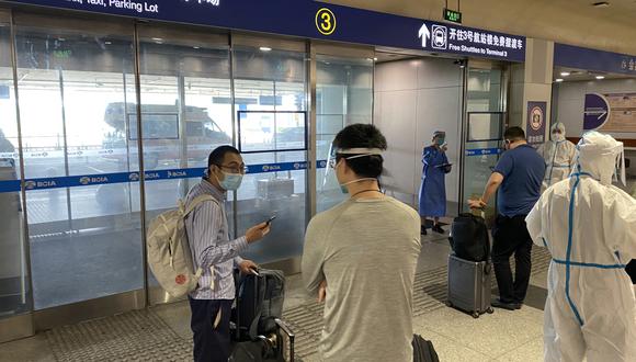 Esta foto tomada el 18 de junio de 2022 muestra a los pasajeros entrantes que esperan ser llevados a destinos designados en cuarentena desde el Aeropuerto Internacional de Beijing. (Foto: Leo RAMIREZ / AFP)