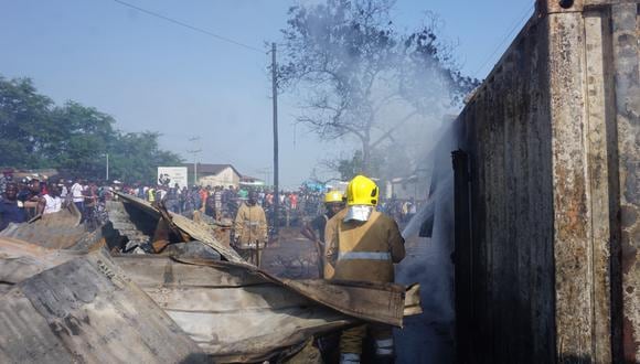 Los bomberos rocían agua en un contenedor quemado después de la explosión de un camión cisterna de combustible en Freetown (Foto: Saidu BAH / AFP)