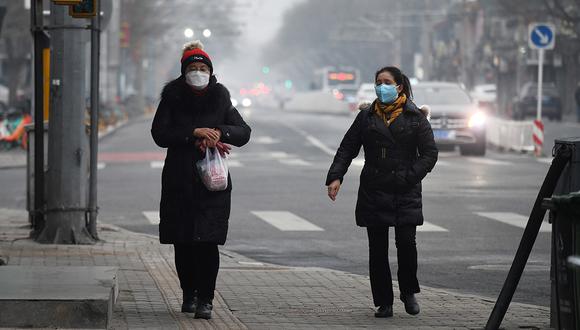Las mujeres usan mascarillas para protegerse contra el coronavirus COVID-19 mientras caminan por una acera en Beijing. (Foto: AFP)