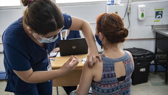 La enfermera chilena María Paz Herreros, de 32 años, quien fue la primera en inocular a un paciente contra el COVID-19 en Chile, inyecta a una mujer la vacuna china Sinovac, en el Hospital Metropolitano de Santiago, el 26 de febrero de 2021. (Foto de MARTIN BERNETTI / AFP).