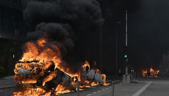 Una fotografía muestra autos ardiendo en la calle al final de una marcha de conmemoración de un conductor adolescente asesinado a tiros por un policía, en el suburbio parisino de Nanterre, el 29 de junio de 2023. (Foto de Alain JOCARD / AFP)