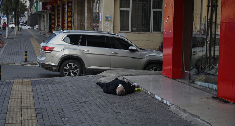 Hombre tendido en el suelo en China (Foto: AFP/Héctor Retamal)