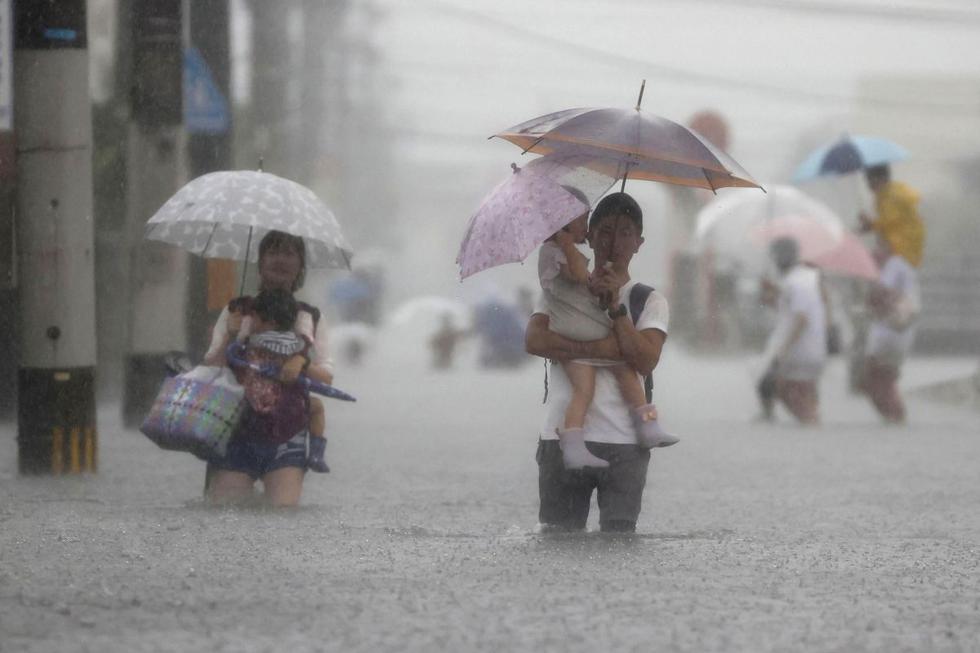 La gente camina por una carretera inundada por fuertes lluvias en Kurume, prefectura de Fukuoka, oeste de Japón, el sábado 14 de agosto de 2021. (Kyodo News/AP).