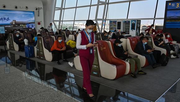 Una trabajadora de una aerolínea revisa su teléfono en el Aeropuerto Internacional Tianhe en Wuhan, provincia central de Hubei en China, el 25 de octubre de 2021. (Foto: Hector RETAMAL / AFP)
