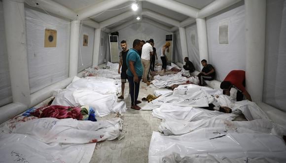 Personas frente a los cuerpos de palestinos muertos después de que un ataque golpeara el hospital Ahli Arab en el centro de Gaza, el 17 de octubre de 2023. (Foto de Dawood NEMER / AFP).