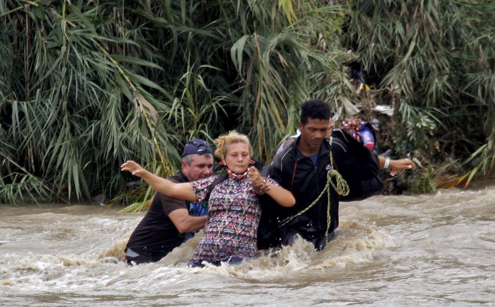 UJna mujer es ayudada a cruzar el río Táchira, la frontera natural entre Colombia y Venezuela. (Foto: SCHNEYDER MENDOZA / AFP)