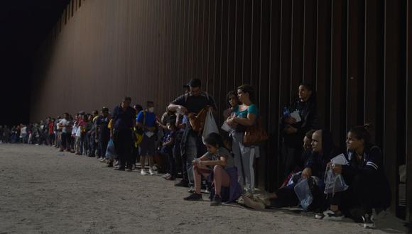 Migrantes hacen fila mientras esperan ser procesados por la Patrulla Fronteriza de EE. UU. después de cruzar ilegalmente la frontera entre EE. UU. y México en Yuma, Arizona, en la madrugada del 11 de julio de 2022. (Foto de allison cena / AFP)