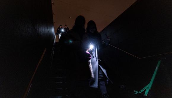 Los peatones encienden sus linternas cuando ingresan a un paso subterráneo durante un corte de energía en el centro de Kyiv el 10 de noviembre de 2022, en medio de la invasión rusa de Ucrania. (Foto de Dimitar DILKOFF / AFP)
