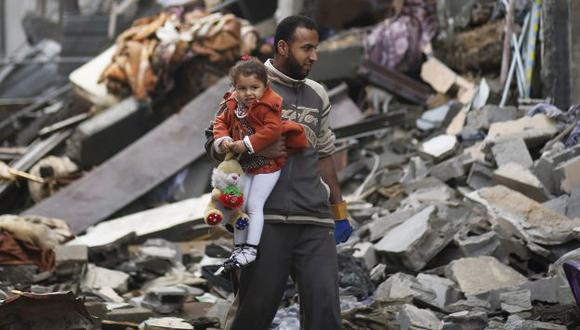 Hombre palestino carga a su hija entre los escombros que dejó un bombardeo israelí en Gaza. (Reuters)