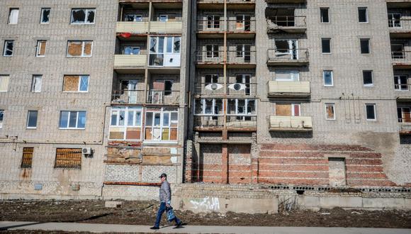 Un hombre pasa frente a un edificio abandonado en la ciudad de Avdiivka, en la región de Donetsk, en la primera línea del este de Ucrania con los separatistas respaldados por Rusia el 21 de febrero de 2022. (Foto de Aleksey Filippov / AFP)