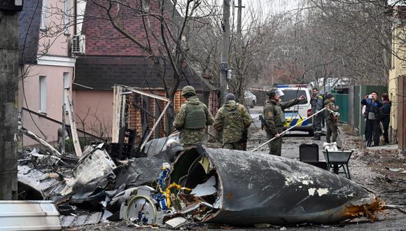 Militares ucranianos trabajan junto a los restos de un avión no identificado que se estrelló contra una casa privada en un área residencial en Kiev el 25 de febrero de 2022. (Foto de GENYA SAVILOV / AFP)