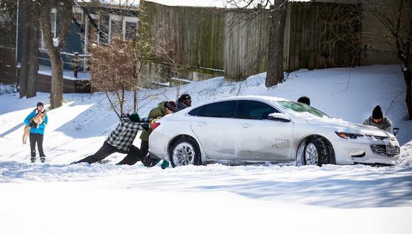 Los residentes del este de Austin empujan un automóvil fuera de la nieve el 15 de febrero de 2021 en Austin, Texas. (Foto de Montinique Monroe/AFP).