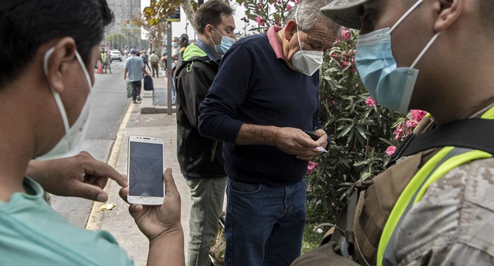 Un soldado mira el celular de un peatón en un retén de Santiago (Chile), el 25 de marzo de 2021, en medio de la pandemia de COVID-19. (MARTIN BERNETTI / AFP).