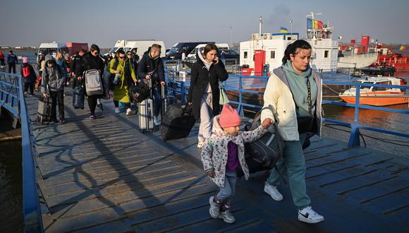 Refugiados de Ucrania caminan por el embarcadero después de llegar en ferry al punto fronterizo rumano-ucraniano Isaccea-Orlivka el 24 de marzo de 2022. (Foto de Daniel MIHAILESCU / AFP)