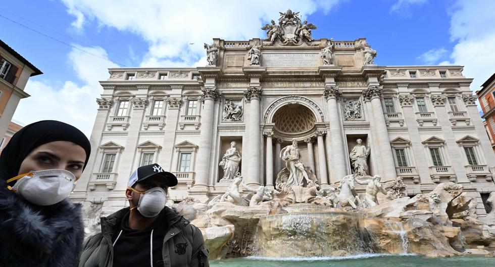 Imagen referencial. Los turistas usan máscaras protectoras contra el coronavirus frente a la fuente de Trevi, en el centro de Roma, Italia. (AFP / Alberto PIZZOLI).