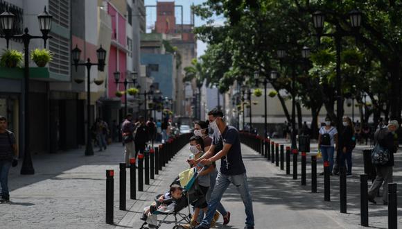 Las personas usan máscaras faciales mientras caminan por el centro de la ciudad después de que el gobierno alivió un bloqueo nacional como medida preventiva contra el coronavirus. (AFP / Federico PARRA).