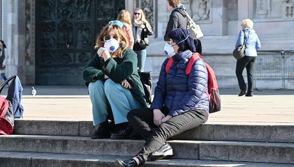 Personas usan una máscara respiratoria en los escalones del cementerio de la Catedral del Duomo de Milán, debido a medidas de seguridad contra el Coronavirus, también conocido como Covid-19. (Foto: AFP)