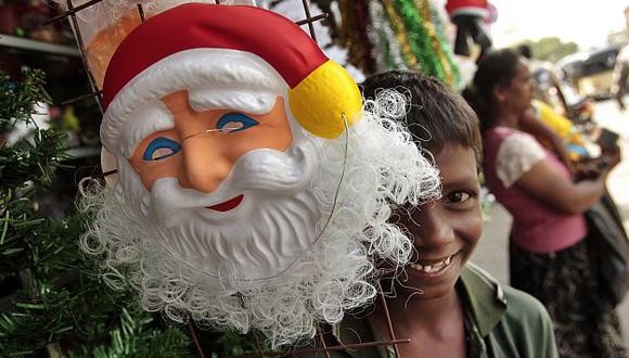 SRI LANKA. Un niño sonríe junto a una máscara de Santa en una feria navideña en una calle de la ciudad de Colombo. (AP)
