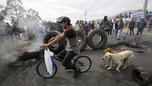 Un joven monta su bicicleta, mientras manifestantes cierran la carretera Panamericana durante una protesta contra la eliminación de los subsidios al combustible en Ecuador. (Foto: AP)
