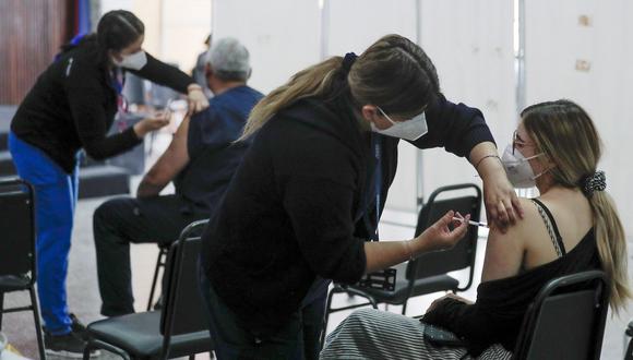 Personas reciben una dosis de la vacuna Pfizer-BioNTech contra el COVID-19 en un centro de vacunación de Santiago, el 20 de enero de 2022. (Foto: JAVIER TORRES / AFP)