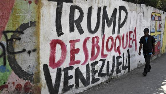 Nicolás Maduro suspendió el diálogo por el bloqueo de Estados Unidos y el apoyo de Juan Guaidó a estas. En la foto, un muro con la pinta "Trump desbloquea a Venezuela" en Caracas. (Foto: AFP)