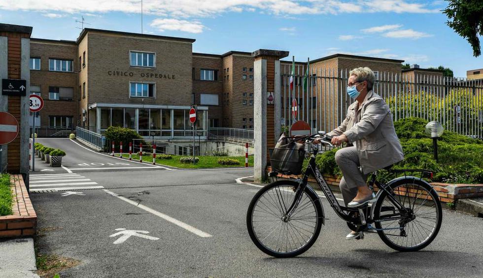 Una residente monta su bicicleta frente al hospital municipal el 20 de mayo de 2020 en Codogno (Italia). (AFP / Miguel MEDINA).