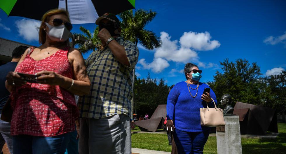 Yrayda Guanipa, de 58 años, (derecha) hace fila para votar en la Biblioteca Regional de Westchester en Miami, el 23 de octubre de 2020. (CHANDAN KHANNA / AFP).