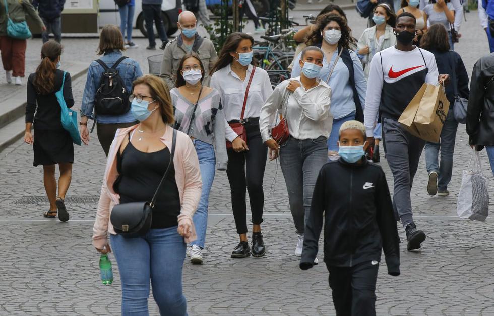 Las personas caminan en un área comercial con máscaras protectoras como precaución contra el coronavirus en París. (AP/Michel Euler).