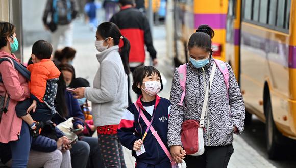 Los niños son escoltados desde la escuela en Hong Kong el 11 de enero de 2022, cuando la ciudad anunció la suspensión de todas las escuelas primarias y de jardín de infantes hasta después del Año Nuevo Lunar a principios de febrero, luego de un brote de coronavirus variante de Omicron. (Foto de Peter PARQUES / AFP)