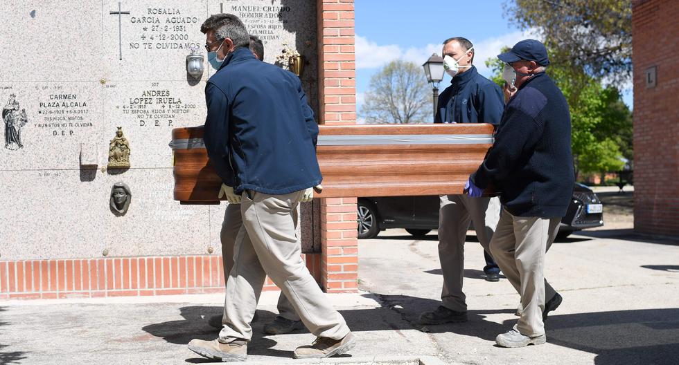 Trabajadores de una funeraria llevan el ataúd de una víctima de coronavirus en un cementerio de Madrid. (AFP / OSCAR DEL POZO / Referencial).