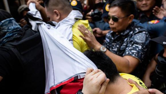Un policía (vestido con una camisa amarilla), que participó en el asesinato de Kian delos Santos en 2017, es escoltado fuera del tribunal de primera instancia de Caloocan en Manila. (Foto: AFP)