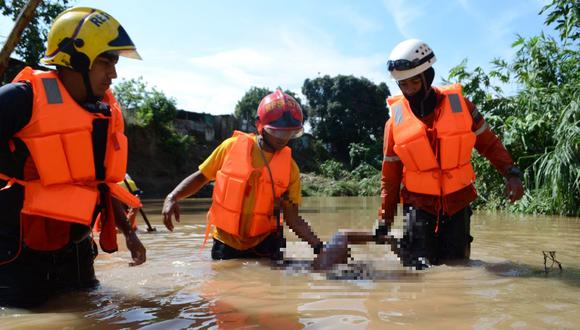 Contenido gráfico. Miembros de Protección Civil sostienen a un hombre fallecido después de una inundación en Barquisimeto, estado Lara, Venezuela, el 28 de septiembre de 2022. (Foto de Nestor VIVAS / AFP)