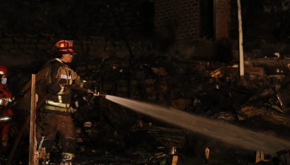 Un bombero sofoca las llamas durante el incendio registrado la noche del viernes en Villa María del Triunfo.