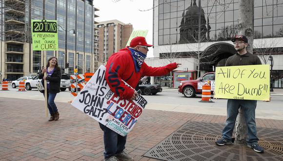 Un hombre discute con un manifestante contra el confinamiento como medida contra el coronavirus frente al Capitolio del Estado en Madison, Wisconsin. (Foto: AFP/KAMIL KRZACZYNSKI)
